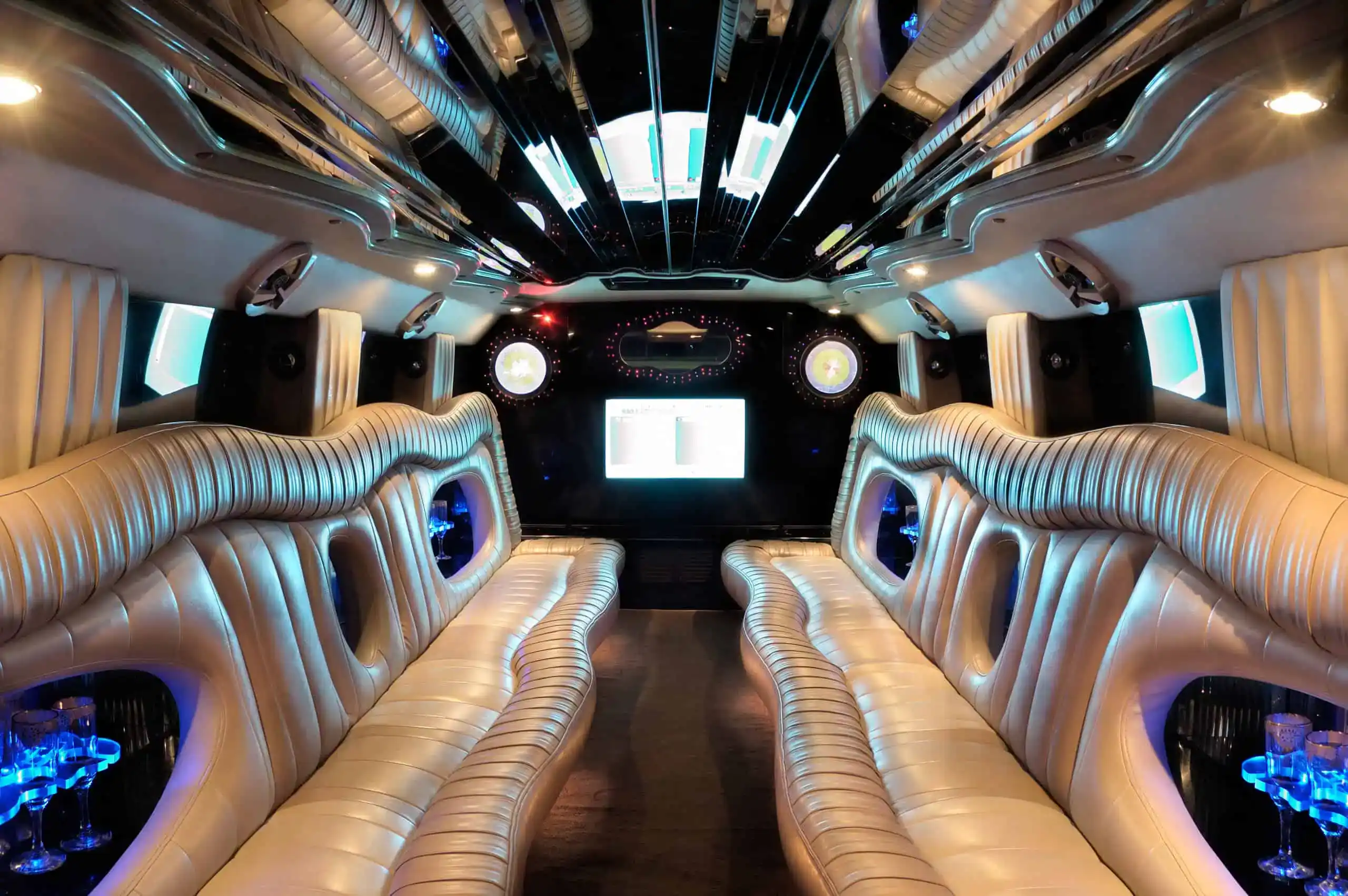 Luxury limousine interior featuring leather seating, ambient lighting, entertainment screens, and upscale chauffeur transportation amenities.