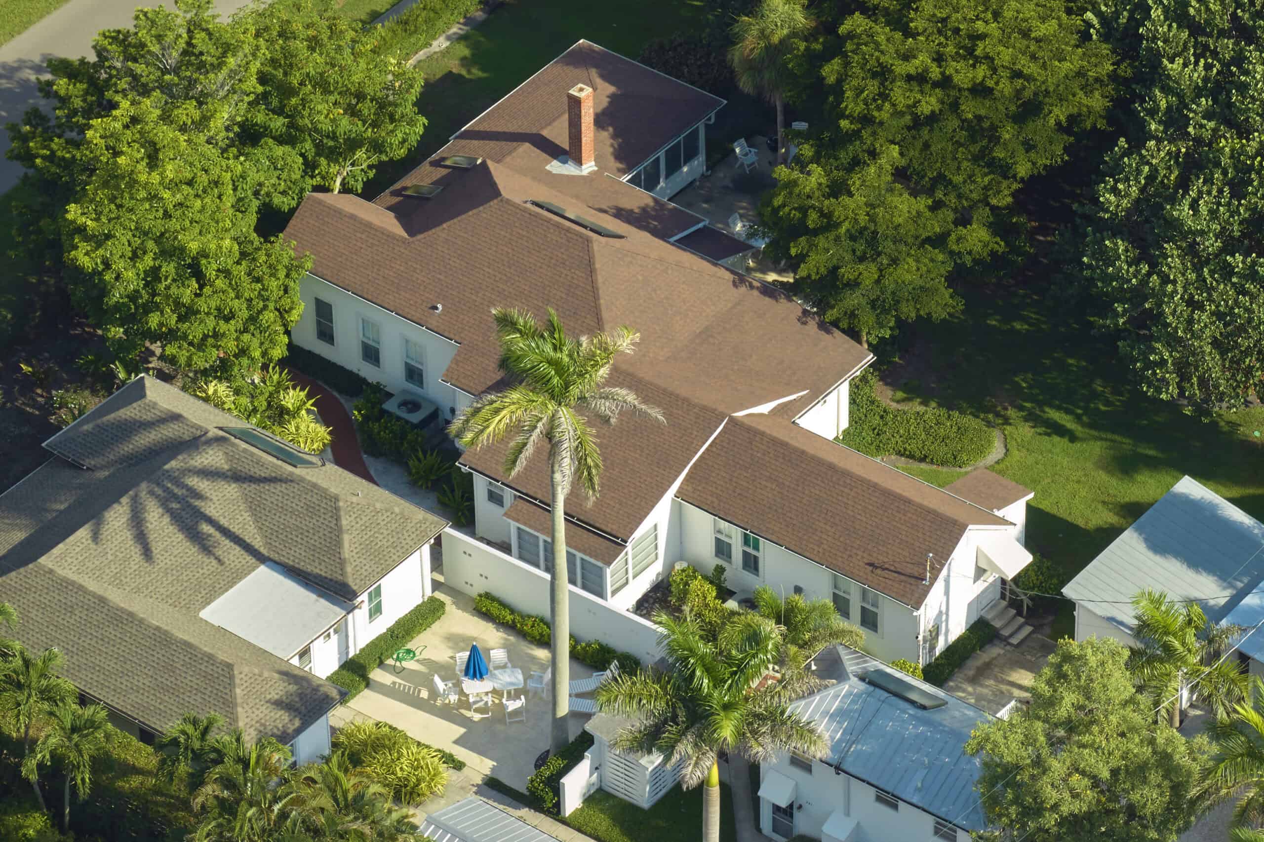 Aerial view of a luxury residential property surrounded by tropical landscaping and neighboring homes in Coral Gables, Florida.